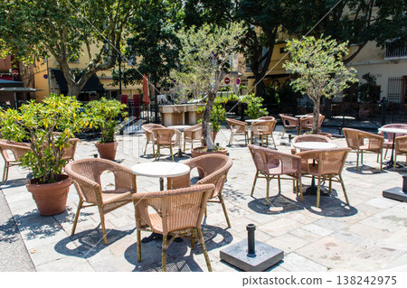 Chairs and tables lined up in a restaurant bathed in bright sunlight; a street scene on the French island of Corsica in the Mediterranean Sea. Chairs and tables lined up in a restaurant bathed in bright sunlight; a street scene on the French island of Corsica in the Mediterranean Sea. 138242975