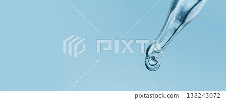 Dropper dispensing single clear liquid drop against blue banner Dropper dispensing single clear liquid drop against blue banner 138243072