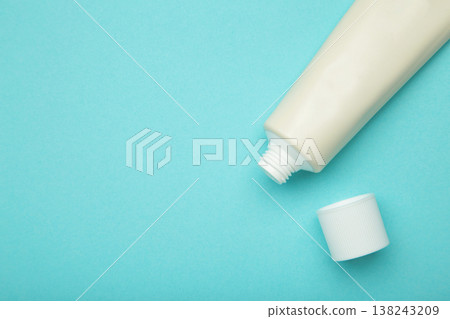 Beige tube of cream on blue background. Mockup plastic tube for cosmetics. Space for text 138243209