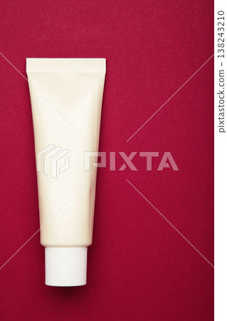 Beige tube of cream on dark red background. Mockup plastic tube for cosmetics Beige tube of cream on dark red background. Mockup plastic tube for cosmetics 138243210