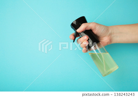 Hand holding oil glass sprayer for cooking on blue background. Space for text Hand holding oil glass sprayer for cooking on blue background. Space for text 138243243