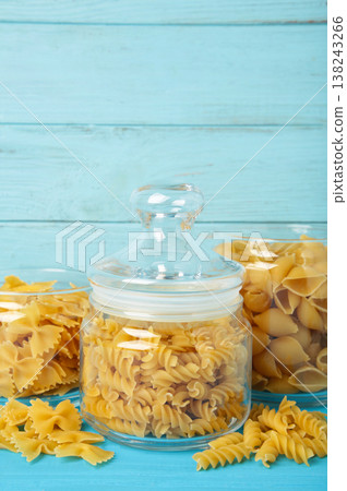 Different types of pasta in glass jars on blue background Different types of pasta in glass jars on blue background 138243266