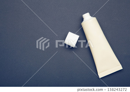 Beige tube of cream on dark blue background. Mockup plastic tube for cosmetics. Space for text 138243272