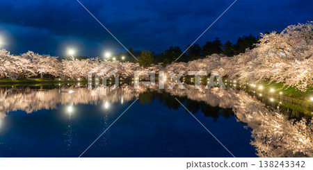 Nighttime cherry blossom illumination at Hirosaki Park's Nishibori moat and its mirror-like reflection on the water's surface. Nighttime cherry blossom illumination at Hirosaki Park's Nishibori moat and its mirror-like reflection on the water's surface. 138243342