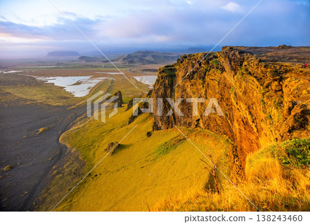 Witness the breathtaking sunset illuminating the Dyrholaey cliffs and Vik beach. The black sand shoreline stretches along the Atlantic, creating a stunning scene in Iceland Witness the breathtaking sunset illuminating the Dyrholaey cliffs and Vik beach. The black sand shoreline stretches along the Atlantic, creating a stunning scene in Iceland 138243460