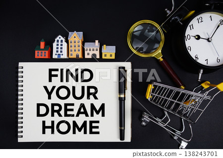 Notepad with the phrase "Find Your Dream Home" surrounded by a pen, mini trolley shopping cart, magnifying glass, clock, and house model 138243701