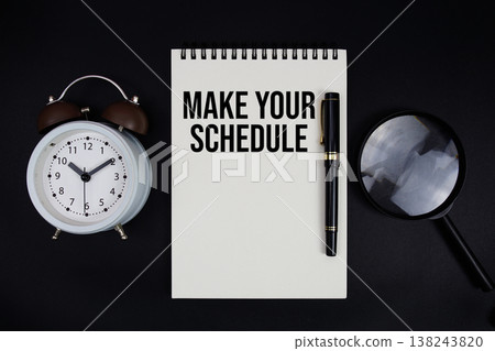 Make Your Schedule text written on notepad with alarm clock top view on black background Make Your Schedule text written on notepad with alarm clock top view on black background 138243820