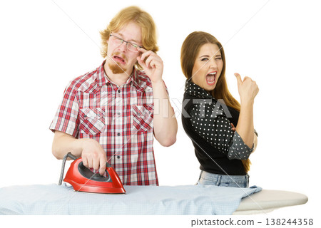 Happy woman and bored man ironing clothes Happy woman and bored man ironing clothes 138244358