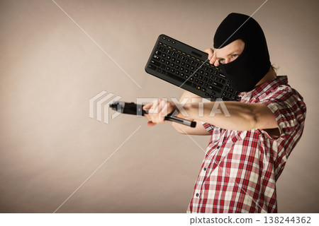 Man in balaclava holding keyboard and gun Man in balaclava holding keyboard and gun 138244362