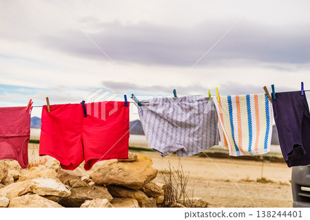 Clothes hang on a line over rocks in a dry area on a cloudy day while the wind moves them gently 138244401