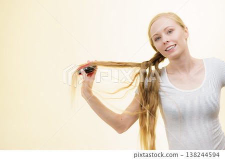 Blonde girl brushing her long hair Blonde girl brushing her long hair 138244594