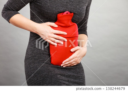 Girl having stomach ache, holding hot water bottle Girl having stomach ache, holding hot water bottle 138244679