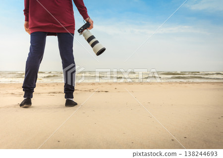 Woman walking on beach with camera 138244693