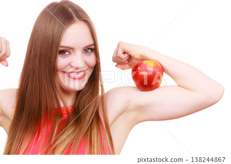 Woman fit girl holds apple fruit on her biceps arm Woman fit girl holds apple fruit on her biceps arm 138244867