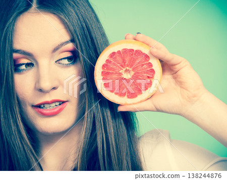 Woman holds half of grapefruit citrus fruit in hand 138244876