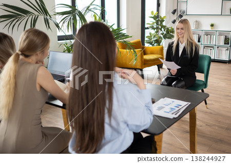Three businesswomen engaged in a professional interview process, with two recruiters intently listening to a confident candidate holding her resume, symbolizing career advancement and hiring Three businesswomen engaged in a professional interview process, with two recruiters intently listening to a confident candidate holding her resume, symbolizing career advancement and hiring 138244927