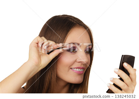 Woman tweezing eyebrows plucking with tweezers Woman tweezing eyebrows plucking with tweezers 138245032