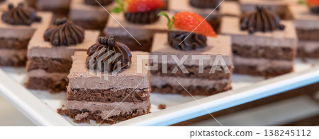 Many pieces of white cake and decorate by pink chocolate heart shape in buffet line. Many pieces of white cake and decorate by pink chocolate heart shape in buffet line. 138245112