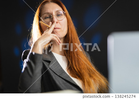 Thoughtful businesswoman planning strategy holding a pencil Thoughtful businesswoman planning strategy holding a pencil 138245274