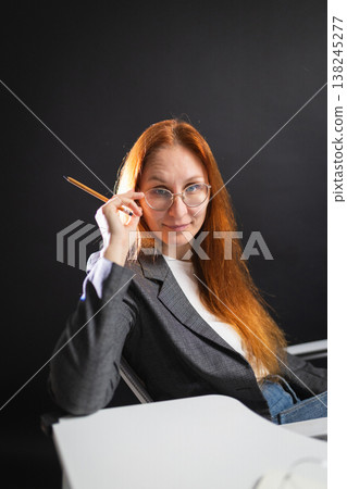 Red haired woman adjusting glasses, thinking at desk 138245277