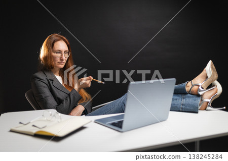 Businesswoman teaching online casually with feet on desk Businesswoman teaching online casually with feet on desk 138245284