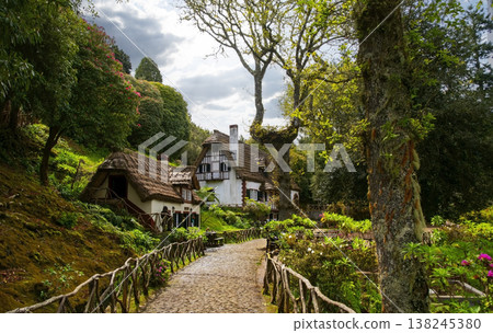 Charming traditional architecture nestled in the verdant hills of Madeira levada PR9 Levada do Caldeirao Verde, featuring a stone path lined with trees and vibrant vegetation 138245380