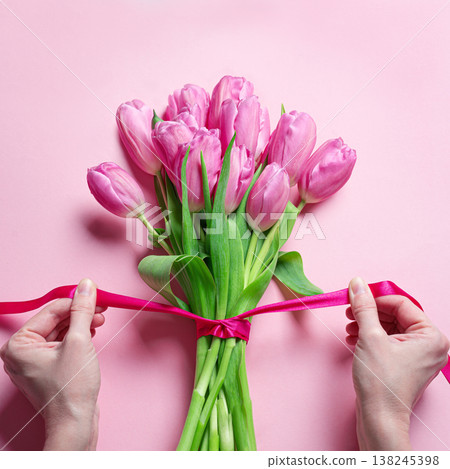 Woman hands tying pink ribbon on tulips, Mother's Day 138245398