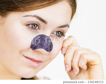 Woman applying pore strips on nose Woman applying pore strips on nose 138246513