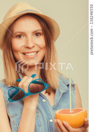 Happy woman in hat holds sunglasses and grapefruit Happy woman in hat holds sunglasses and grapefruit 138246550