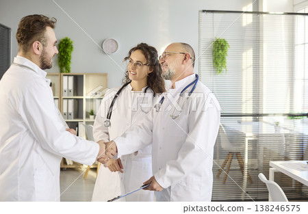 Doctors handshake during team meeting in clinic office, partnership agreement Doctors handshake during team meeting in clinic office, partnership agreement 138246575