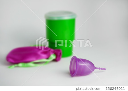Purple menstrual cup lying on a clean surface with a green container and a pink storage pouch, promoting sustainable hygiene Purple menstrual cup lying on a clean surface with a green container and a pink storage pouch, promoting sustainable hygiene 138247011