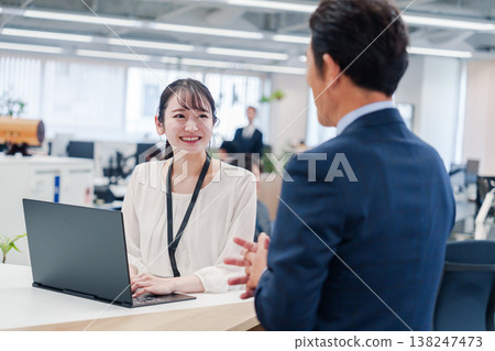 政府辦公櫃檯的女性工作人員正在協助老年顧客。 政府辦公櫃檯的女性工作人員正在協助老年顧客。 138247473