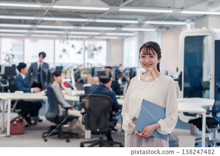 A woman smiling while holding documents in the office 138247482