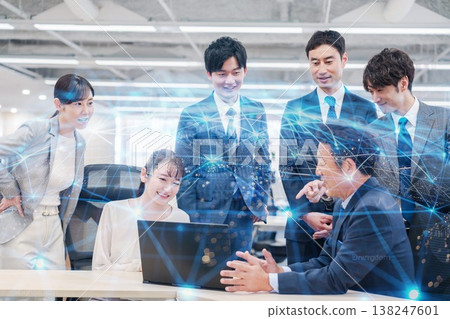 辦公室裡，人們一邊看著電腦一邊進行團隊討論。 138247601