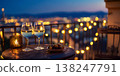 Elegant outdoor balcony dinner setup with wine glasses, candlelight, and city view at dusk 138247791