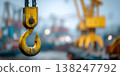 Yellow crane hook in focus with blurred port cranes and bokeh background in logistics industry setting 138247792