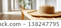 Straw sun hat placed on wooden table in bright indoor setting with natural light 138247795