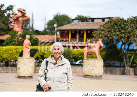 Happy senior lifestyle concept. Senior woman at the central square of the beautiful small town of Raquira. The city of pots in Colombia. 138248246