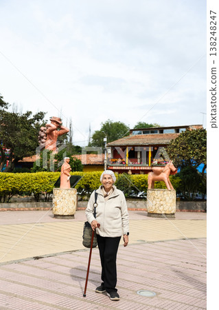 Happy senior lifestyle concept. Senior woman at the central square of the beautiful small town of Raquira. The city of pots in Colombia. 138248247