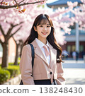 A spring portrait of a woman with a backpack on, smiling gently, against a backdrop of a building under cherry blossoms in full bloom. 138248430