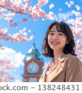 A spring portrait of a woman smiling gently against the backdrop of a clock tower, against a backdrop of a blue sky and cherry blossoms in full bloom. 138248431