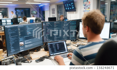 Programmer male developer office computer laptop monitor code software technology Focused male programmer modern office working with laptop and multiple monitor, writing complex code computer 138248671