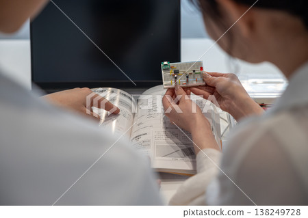 Young men and women studying electronic circuits Young men and women studying electronic circuits 138249728