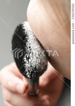 A woman's hands applying makeup; her hands applying powder. A woman's hands applying makeup; her hands applying powder. 138250583