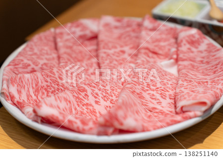 Thinly sliced premium marbled Wagyu beef for shabu-shabu, served on a white plate. Thinly sliced premium marbled Wagyu beef for shabu-shabu, served on a white plate. 138251140