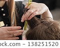 Hairdresser trims wet hair using scissors and comb during a haircut. Close-up of hands and hair sectioning in salon, grooming service, hygiene, and care concept. 138251520