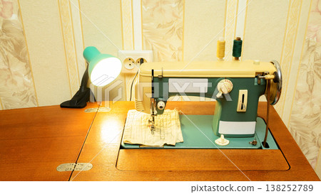 turquoise vintage sewing machine on a wooden table under a lamp in a home setting turquoise vintage sewing machine on a wooden table under a lamp in a home setting 138252789
