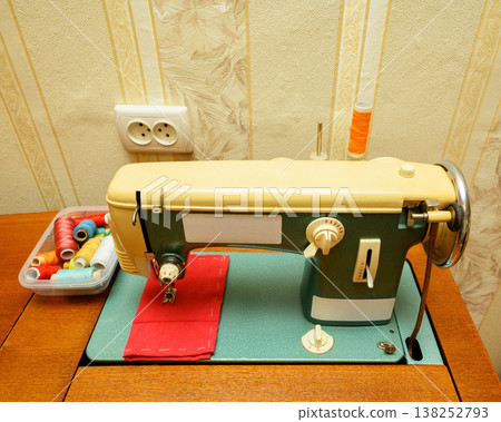 vintage turquoise sewing machine on a wooden table with colorful thread spools in a plastic box vintage turquoise sewing machine on a wooden table with colorful thread spools in a plastic box 138252793