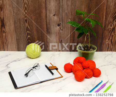 notebook and red yarn balls on a marble table 138252798