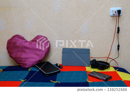 set of portable electronics on a bright patchwork blanket next to a pink heart set of portable electronics on a bright patchwork blanket next to a pink heart 138252888